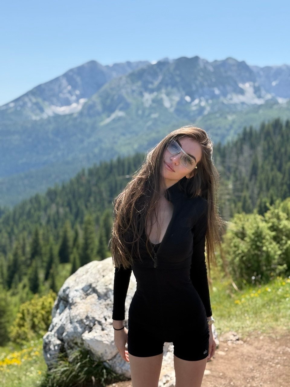 Anna Rey in sunglasses against a mountain landscape